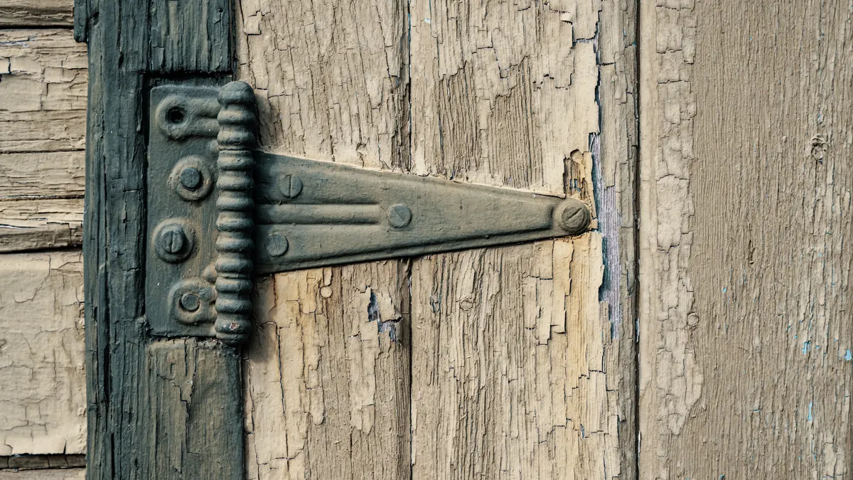Heavy-Duty Ranch Gate Hardware Guide: Hinges, Droppers, and Braces close-up of a gate brace strap on weathered wood