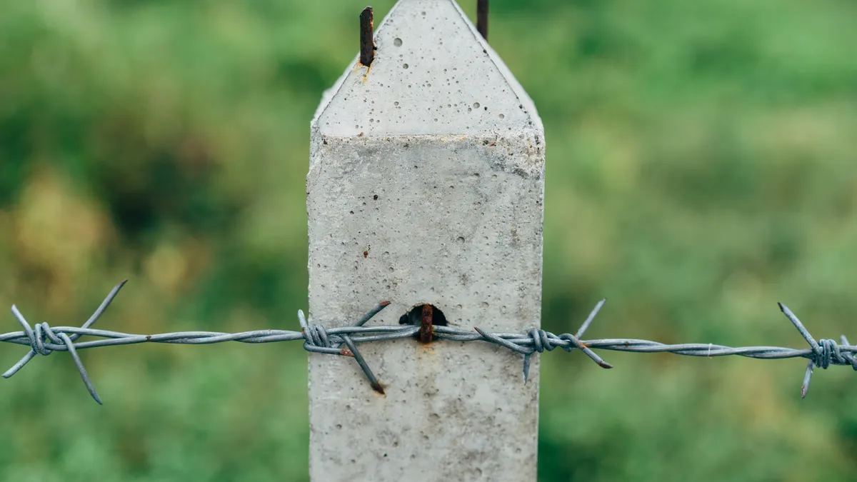 Concrete fence post with barbed wire attached