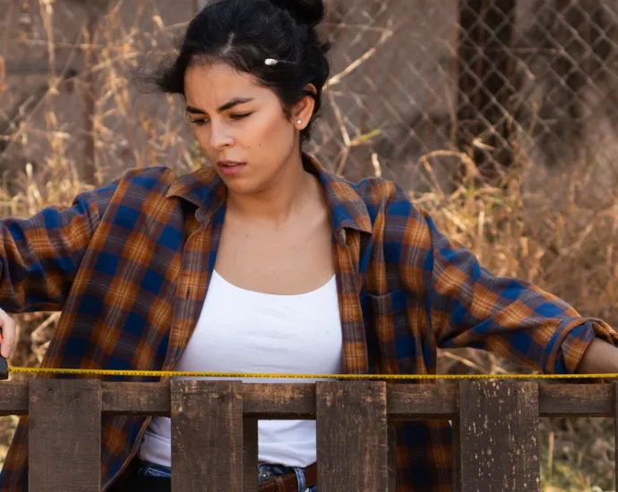 Woman measuring a fence line with a tape measure