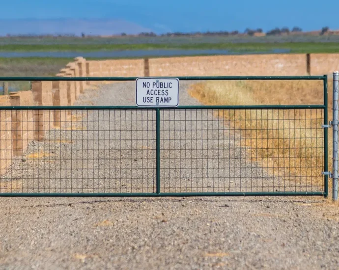 Metal ranch gate across a dirt driveway